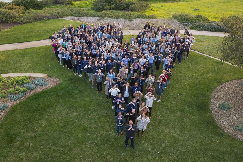 The Kate Farms team gathered on a lawn in the shape of a heart, each person making a heart with their hands.